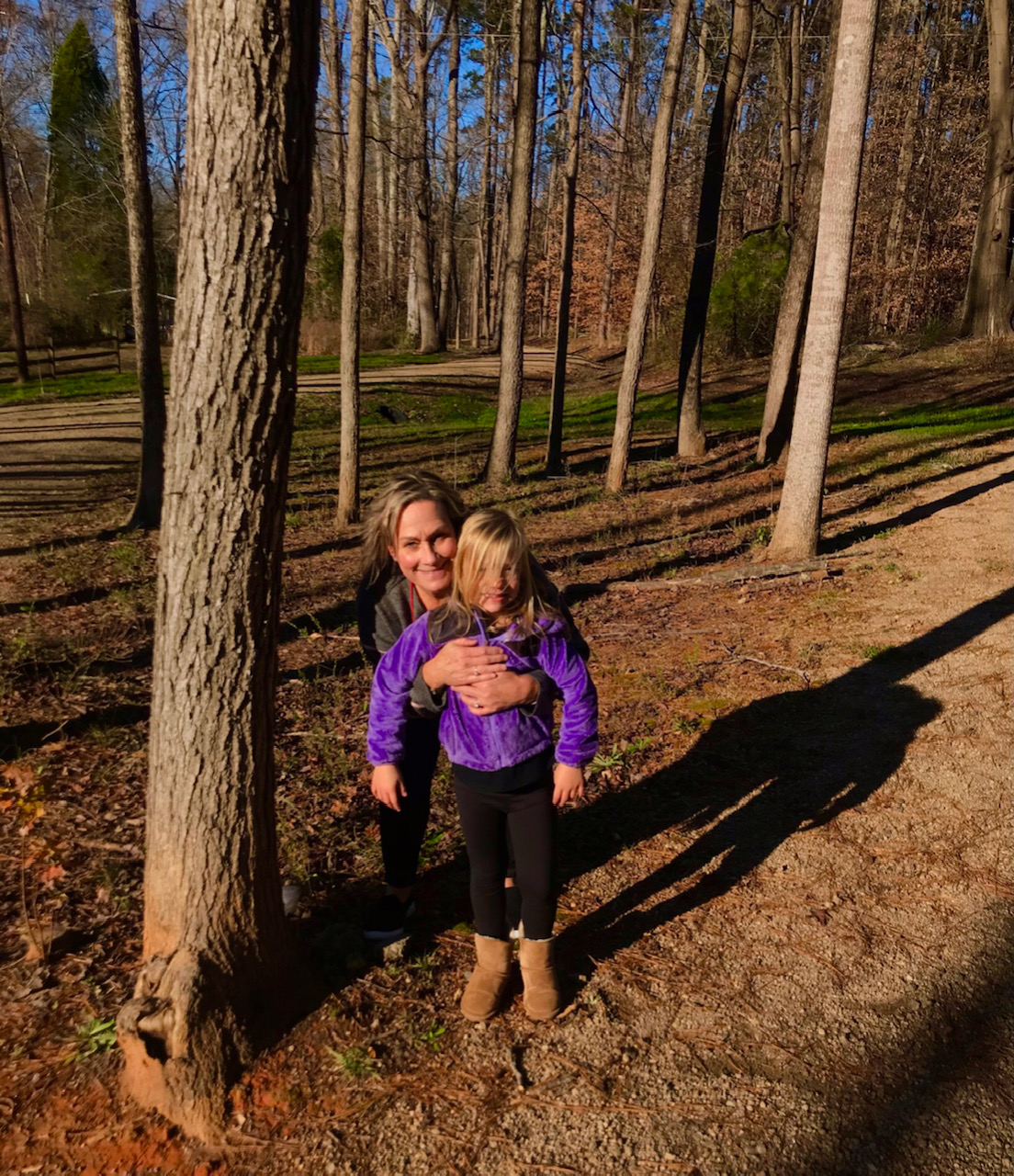 Woman hugging little girl in woods