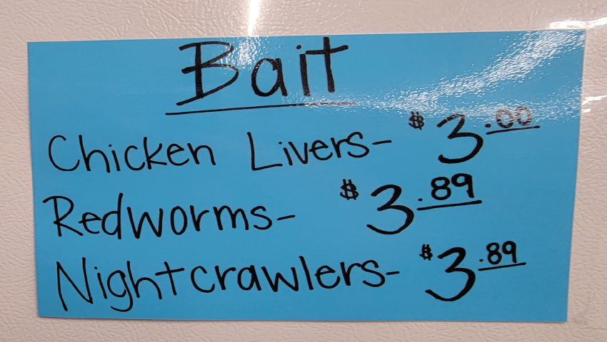 blue handwritten sign for Bait. Chicken Livers $3, Redworms $3.89, and Nightcrawlers $3.89.